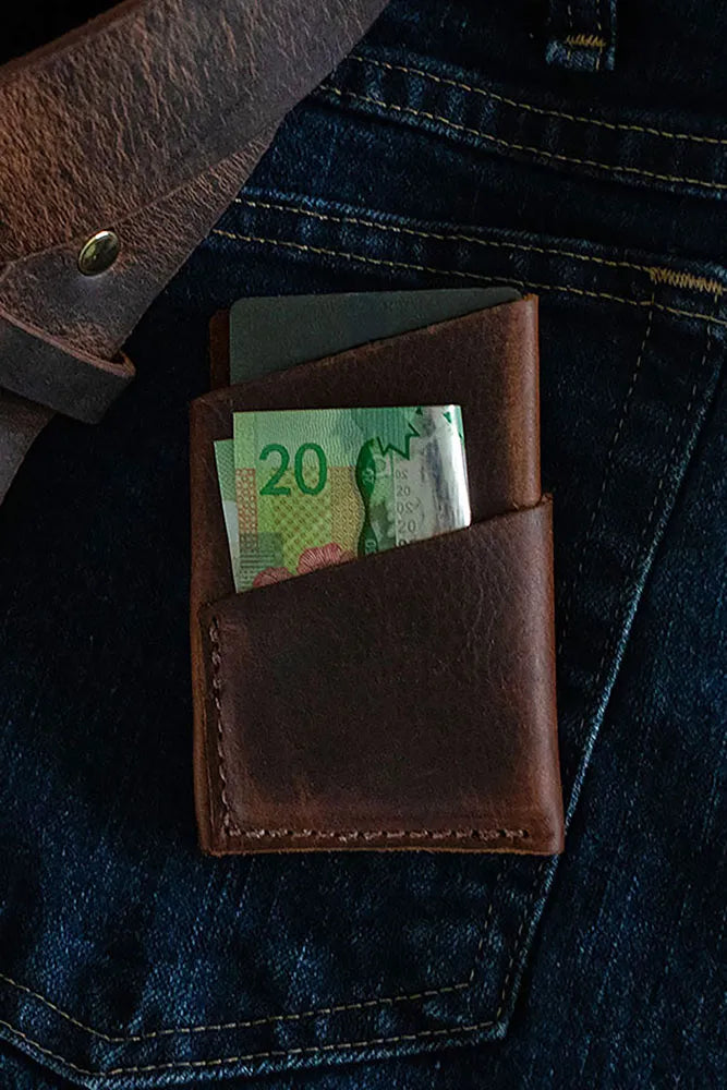 a minimalistic wallet with $20 in it on a pair of jeans