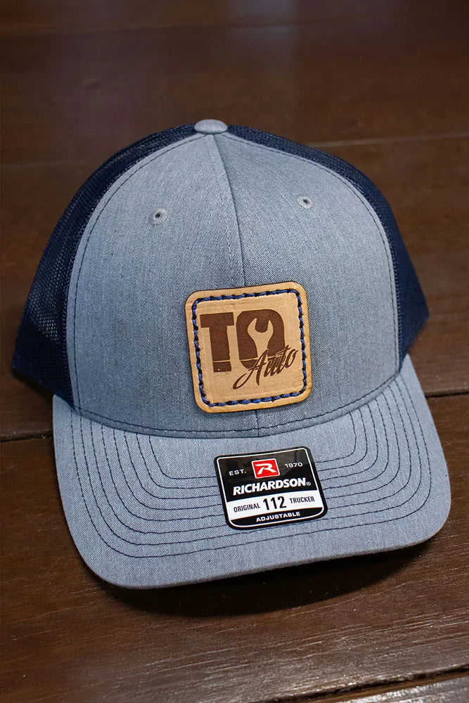 A trucker baseball hat with a leather patch sewn to the front.