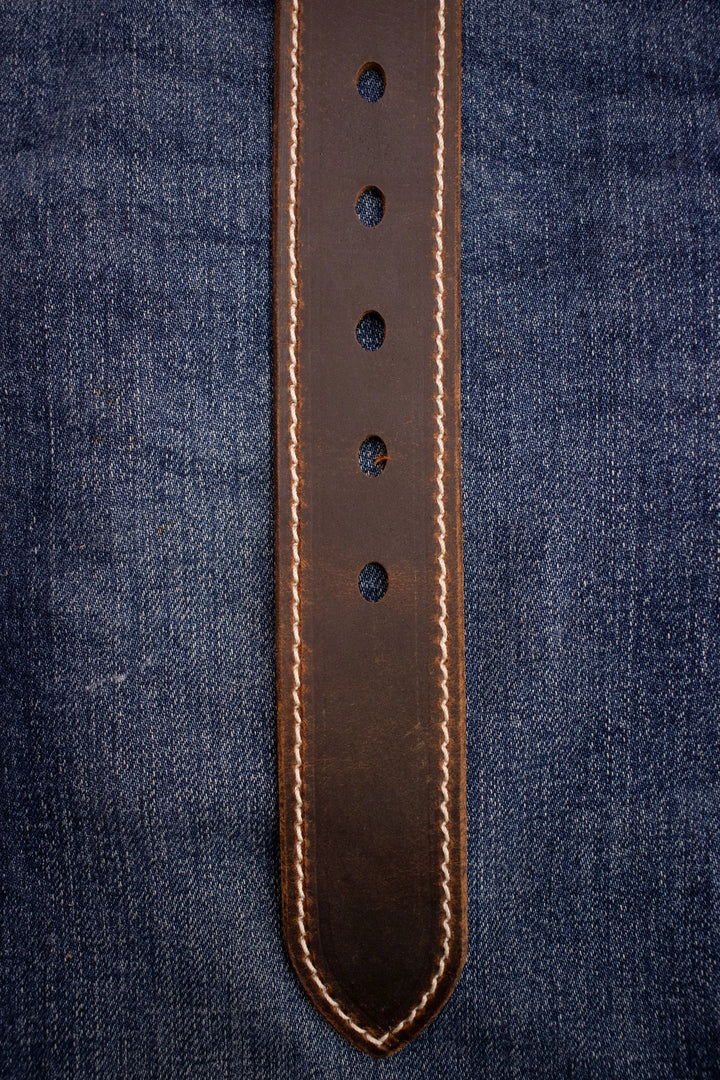 Brown leather belt with stitching on a denim background