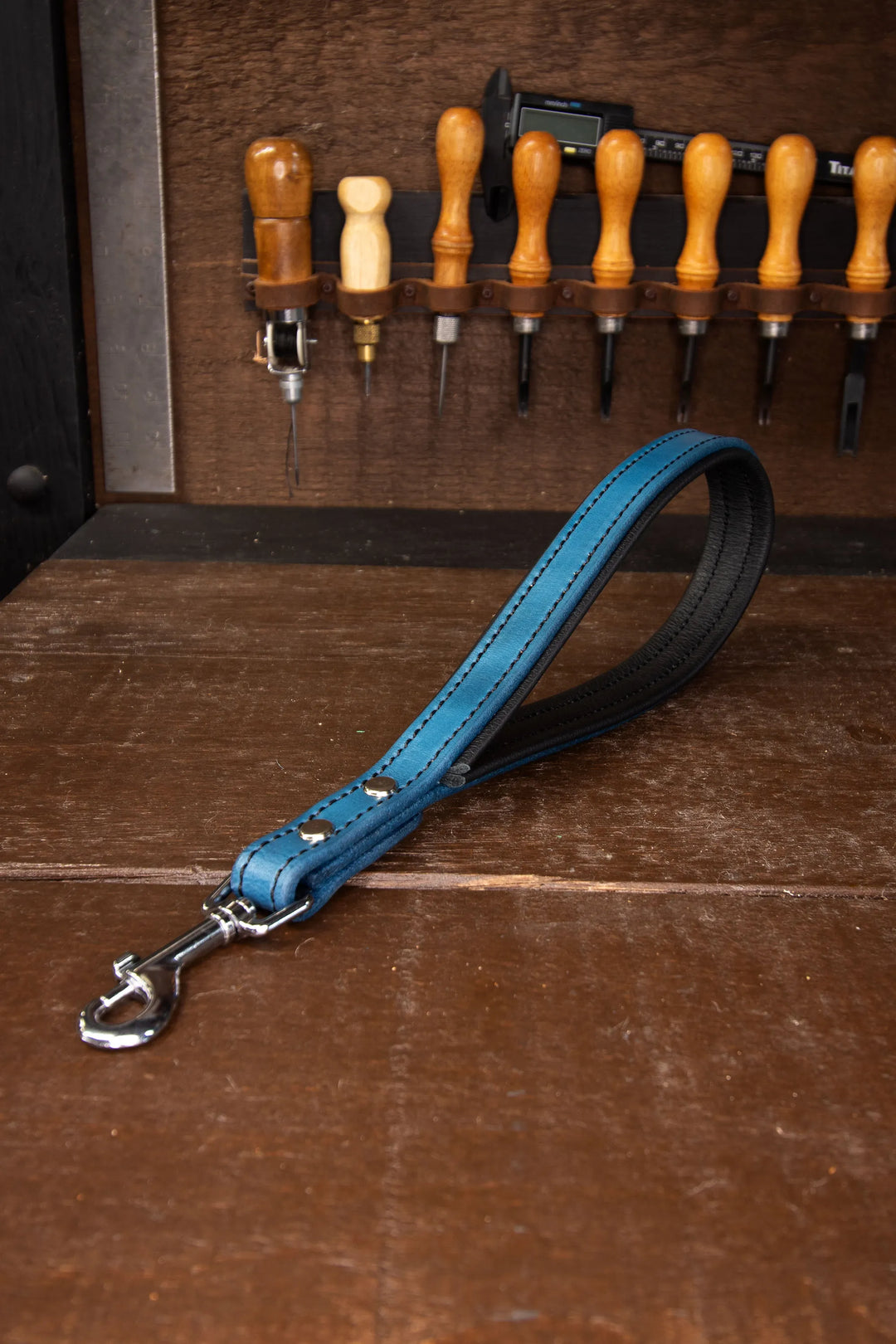 Blue leather dog leash with silver clasp on a wooden background