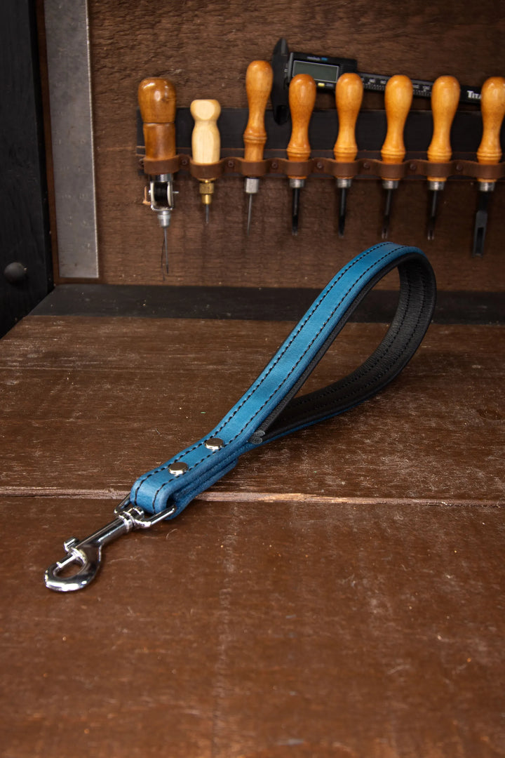 Blue leather dog leash with silver clasp on a wooden background