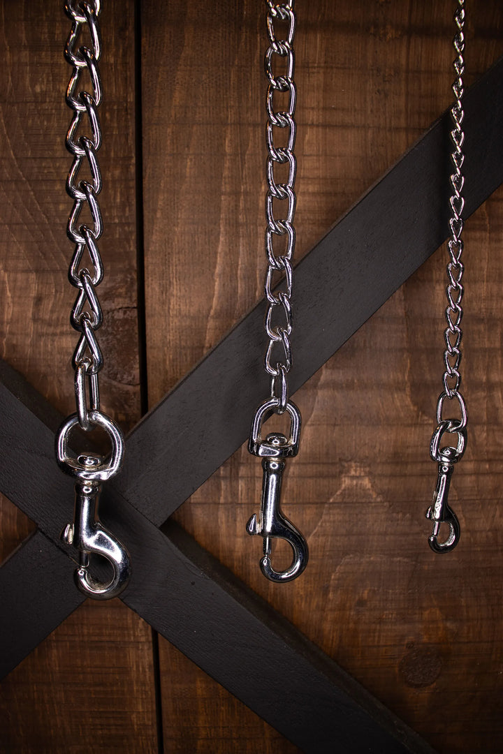 3 chains showing different thicknesses handing in front of a wooden cabinet
