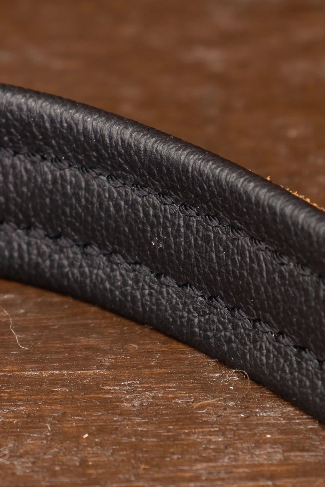 Close-up of black leather padding of leash handle on a wooden surface